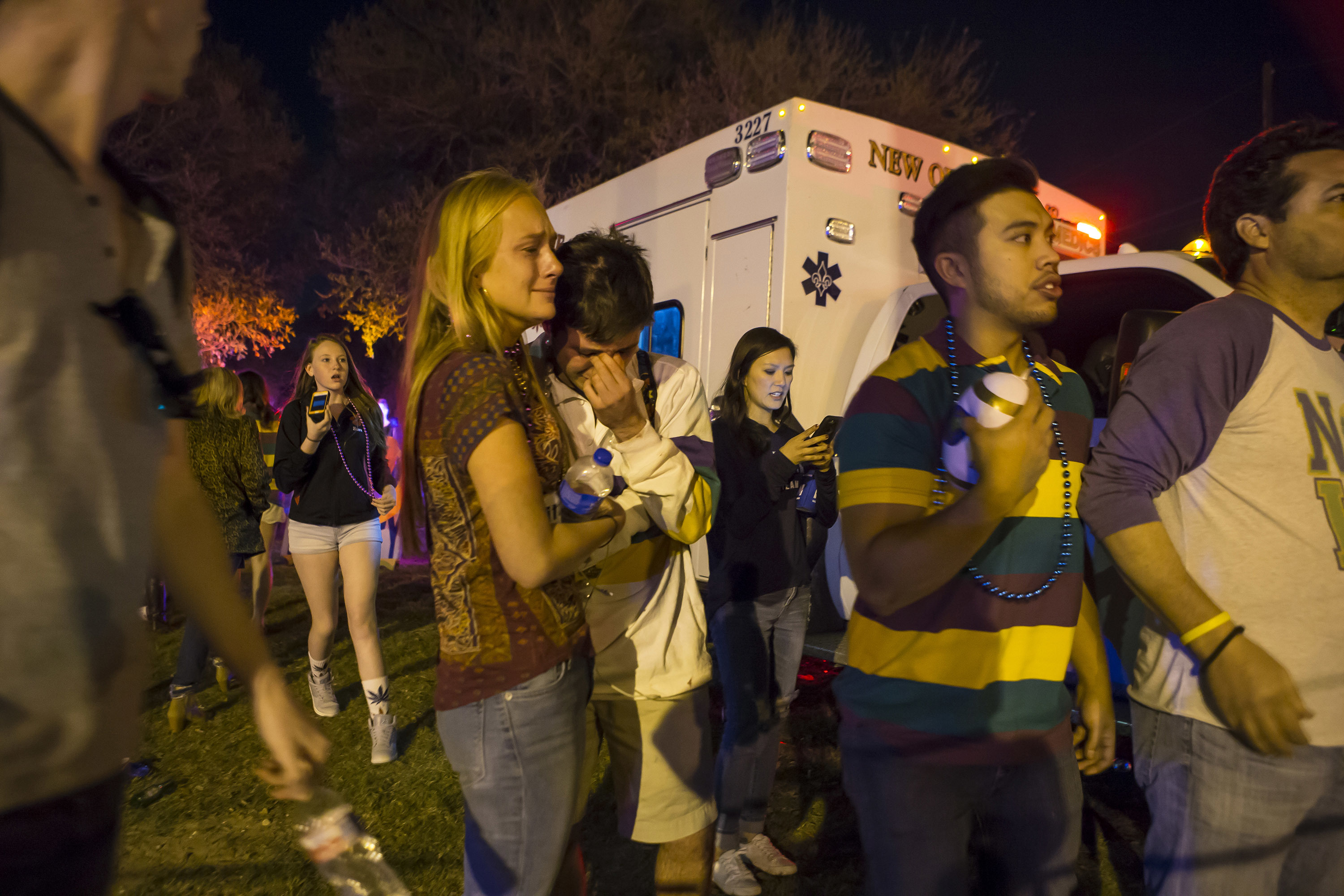 People hug and console each other as they watch New Orleans police work the scene where a vehicle plowed into a crowd injuring multiple people as the Krewe of Endymion parade rolled through New Orleans on Feb. 25, 2017. (Chris Granger/NOLA.com The Times-Picayune via AP)