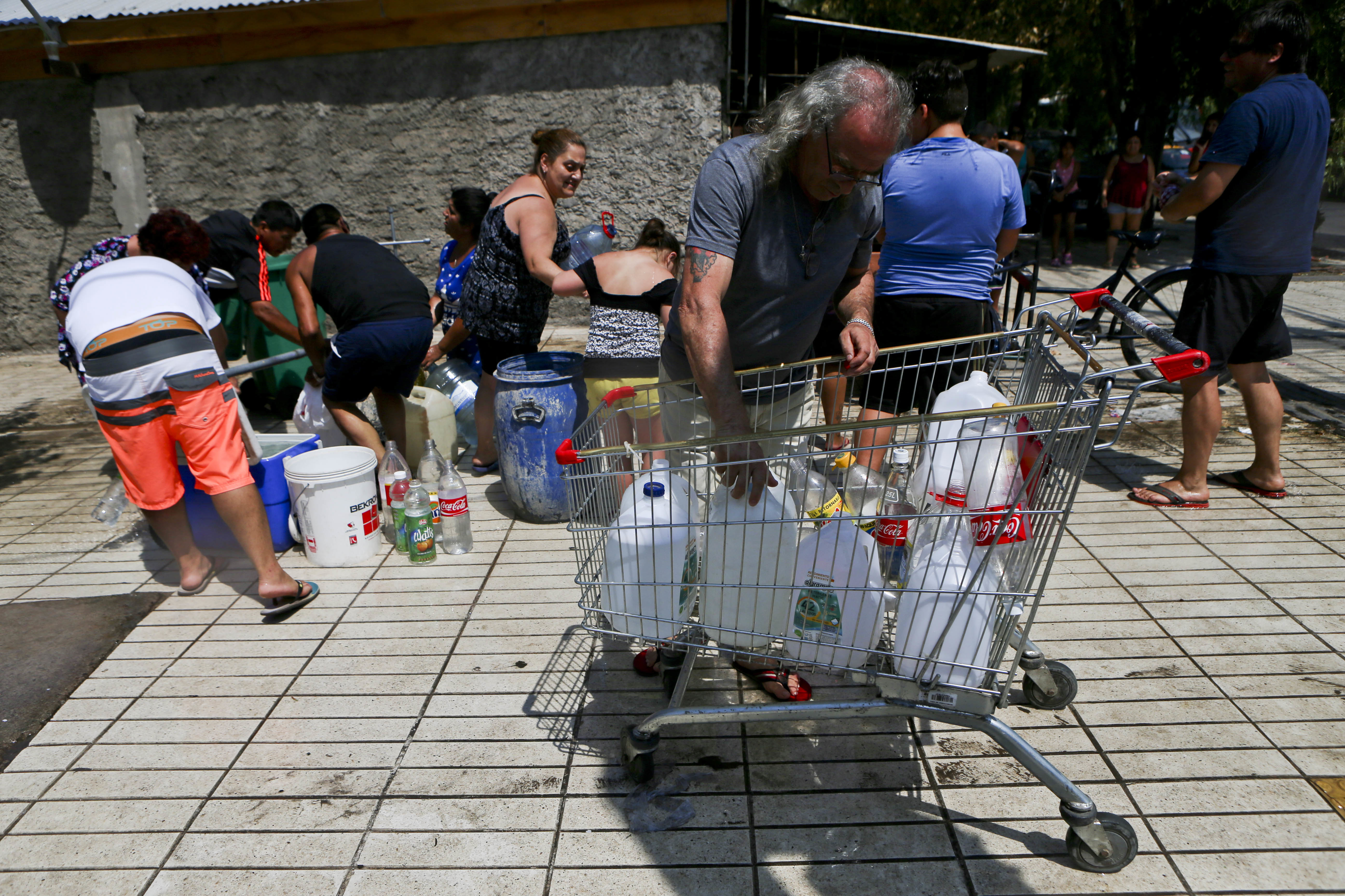 Residents gather water from a fire hydrant at a neighborhood in Santiago, Chile on Feb. 27, 2017. (AP Photo/ Esteban Felix)