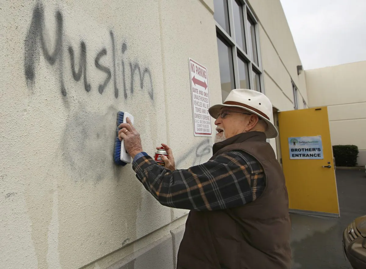 A man cleans up racist graffiti painted on the side of a mosque in what officials are calling an apparent hate crime in Roseville, Calif. on Feb. 1, 2017. (AP Photo/Rich Pedroncelli)