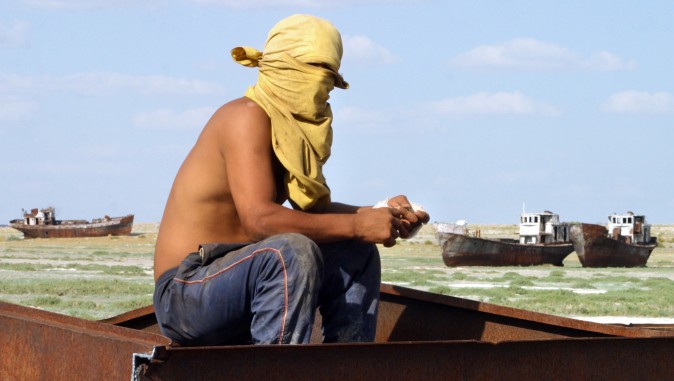 A picture taken 04 August 2005 shows a Kazakh metal robber sitting on a shipwreck at the place called "Sheeps cemetery" in Dzhambul settlement, some 64 kms from town of Aralsk. The ecological disaster on Aral Sea, which had been drying up for the past 40 years, was reached in 1987, when salted lake, which had once been the world's fourth largest, split into two unequal parts. AFP PHOTO / VYACHESLAV OSELEDKO (Photo credit should read VYACHESLAV OSELEDKO/AFP/Getty Images)