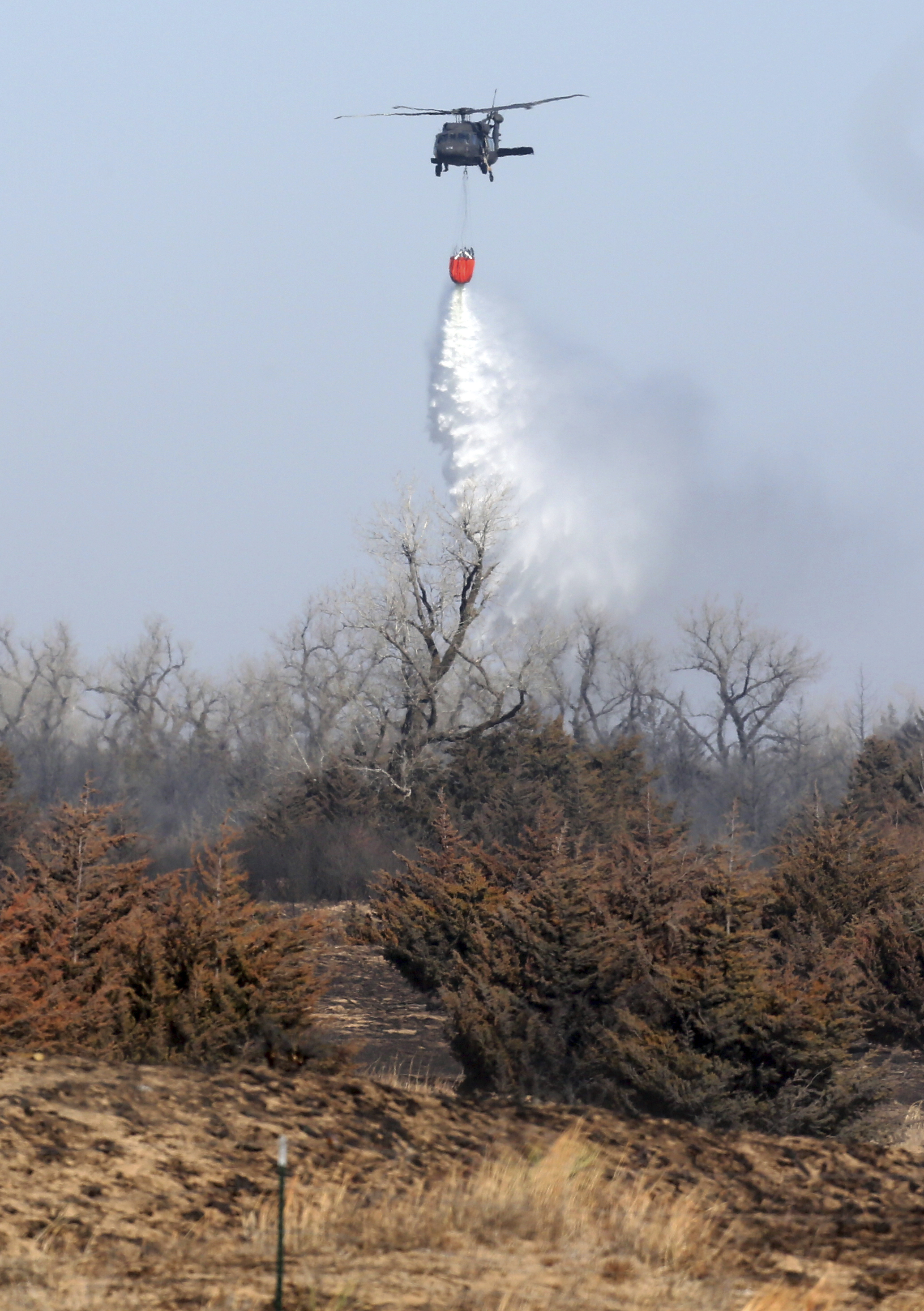 A National Guard helicopter drops water on trees on the west side of the Highlands in Hutchinson, Kan., on March 6, 2017. (Lindsey Bauman/The Hutchinson News via AP)