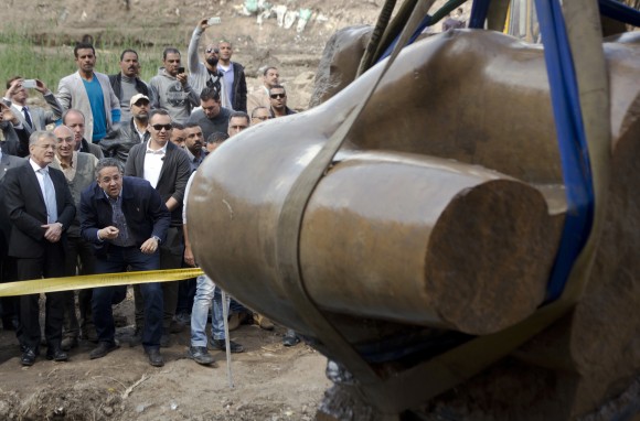 Egyptian Antiquities Minister Khaled el-Anani, second left, and German ambassador to Egypt Julius Georg Luy, left, watch a massive statue, that may be of pharaoh Ramses II, one of the country's most famous ancient rulers, after it was pulled out of groundwater in a Cairo slum, Egypt on March 13, 2017. (AP Photo/Amr Nabil)