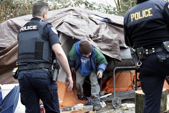 Leroy Henry (C) steps out of his tent in the woods to talk with police officer Kevin Davis, left, and Sgt. Mike Braley in Everett, Wash. on Feb. 16, 2017. As overdose deaths from opioids and heroin spiked the mayor of Everett took steps to tackle the epidemic devastating this working-class city north of Seattle. Mayor Ray Stephanson has spent thousands to clean up streets, hire social workers to ride along with police officers and build permanent housing for the chronically homeless. (AP Photo/Elaine Thompson)