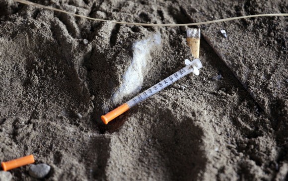 A discarded syringe sits in the dirt with other debris under a highway overpass where drug users are known to congregate in Everett, Wash. on Feb. 16, 2017. (AP Photo/Elaine Thompson)