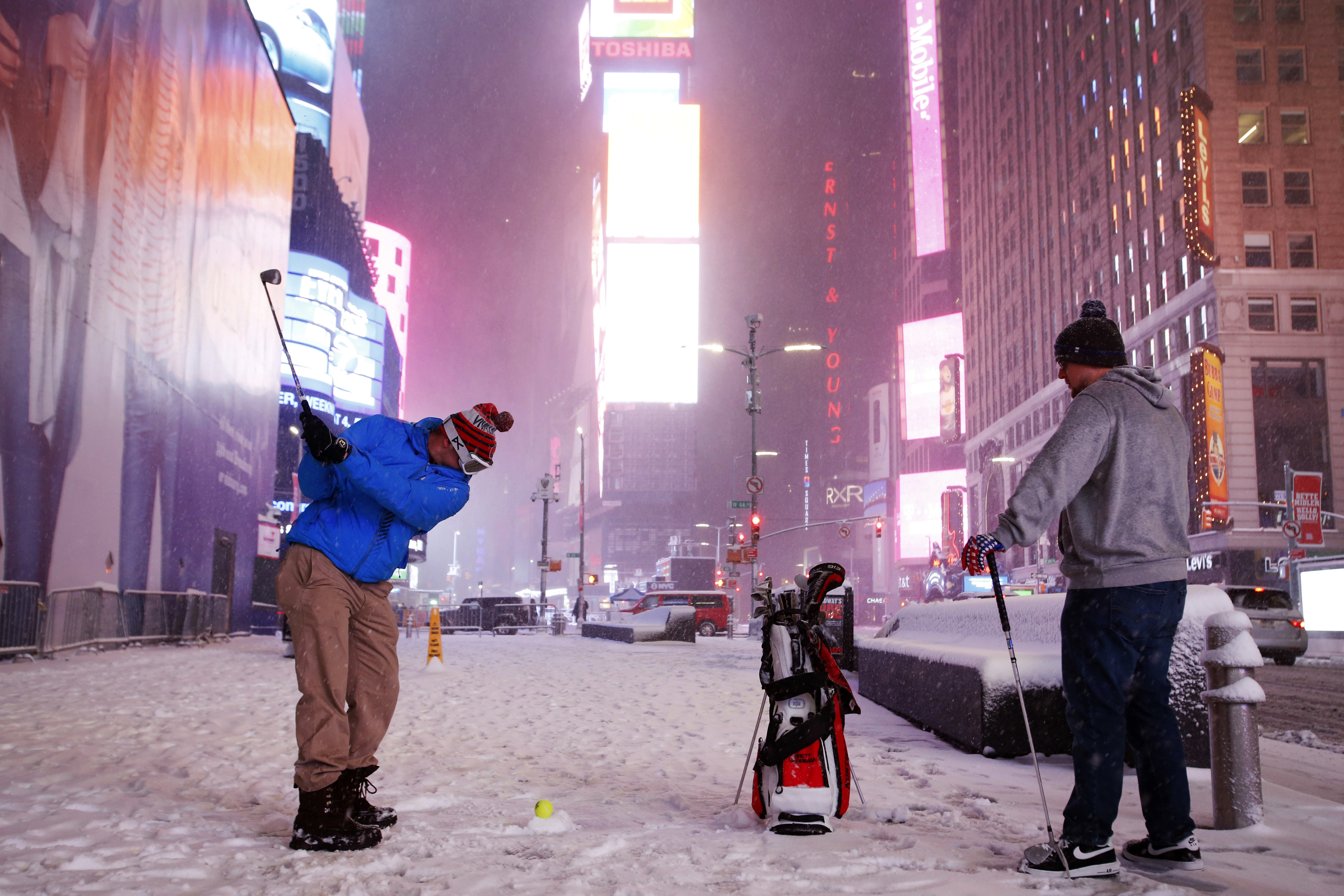 Two men play golf with a tennis ball as a snowstorm sweeps through Times Square on in New York on March 14, 2017. (AP Photo/Mark Lennihan)