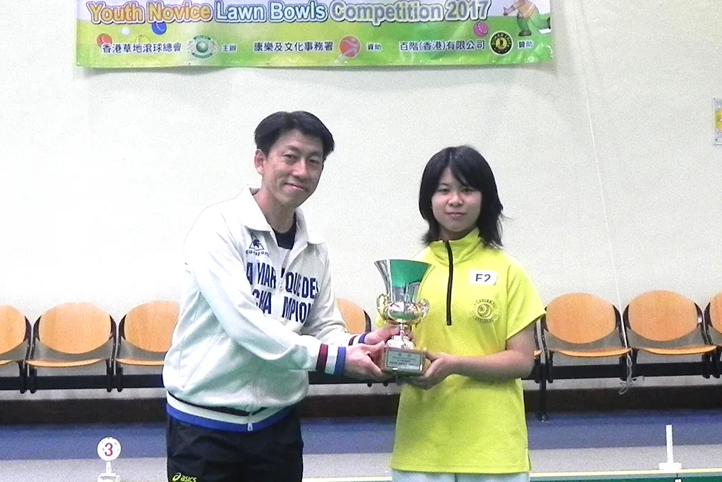 HAPPY GIRL – Thirteen years old Tam Wing Chui, the first girl winner of the Youth Novice Singles competition last Sunday, Mar 14, receives her trophy from Mr Gordon Lui of LCSD. (Howard Poon)