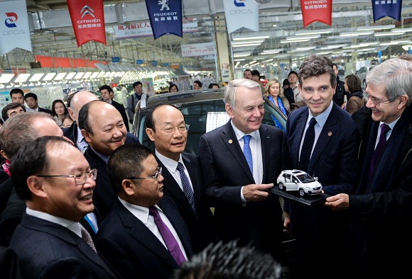 Then-French Prime Minister Jean-Marc Ayrault (3rd R) prepares to present a model car to Chinese managers on a visit to the Dongfeng Peugeot-Citroën Automobile plant on Dec. 7, 2013 in Wuhan,China. The following year, Chinese state-owned Dongfeng became an equal shareholder in PSA Peugeot Citroën, the leading carmaker in France. (PETER PARKS/AFP/Getty Images)