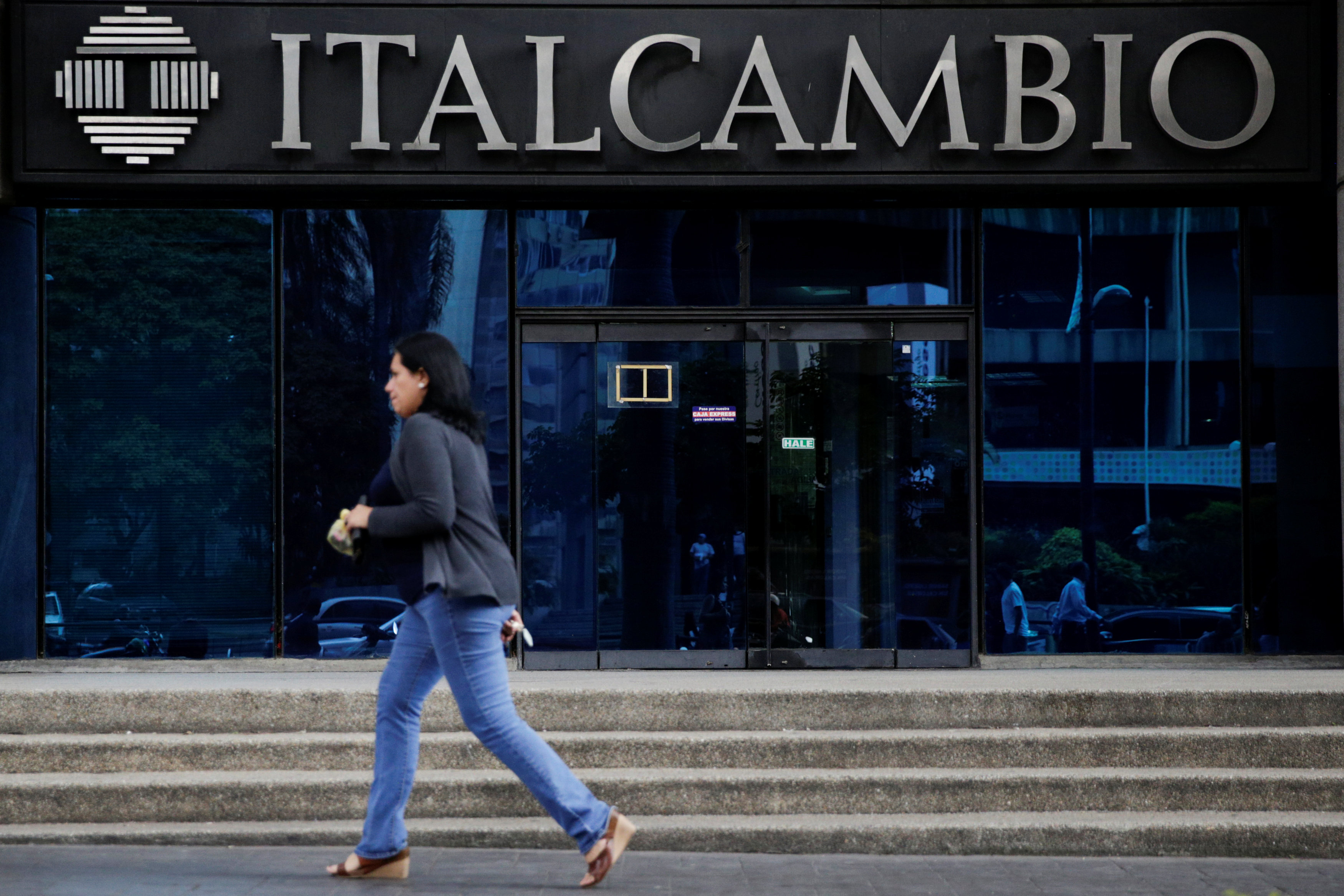A woman walks past a branch of Italcambio currency exchange in Caracas, Venezuela on Feb. 14, 2017. (REUTERS/Marco Bello)