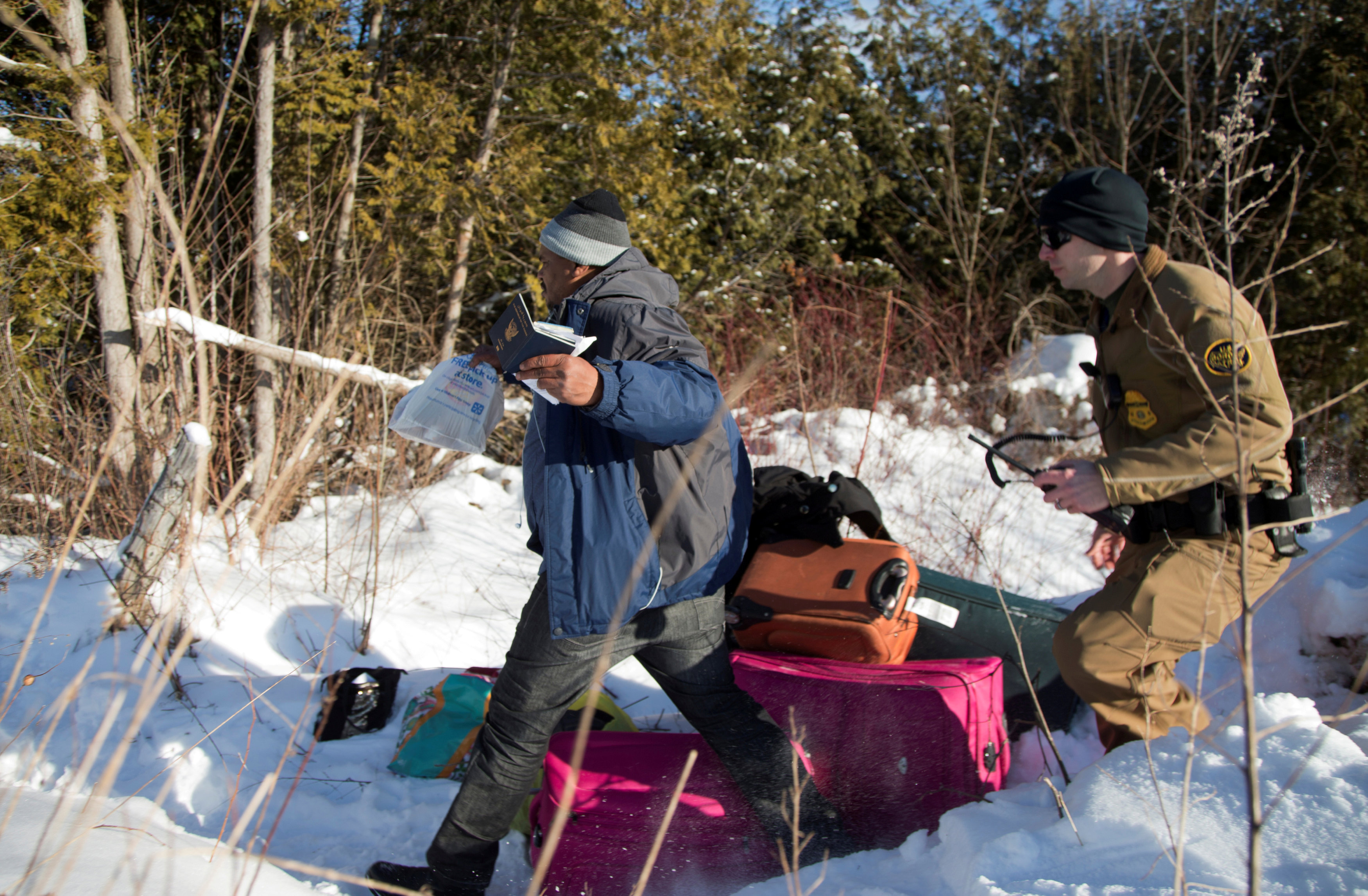 A man who claimed to be from Sudan runs for the border holding his family's passports as he is chased by a U.S. border patrol officer as he was detained after his family crossed the U.S.-Canada border into Hemmingford, Canada, from Champlain in New York, U.S. on Feb. 17, 2017. (REUTERS/Christinne Muschi)
