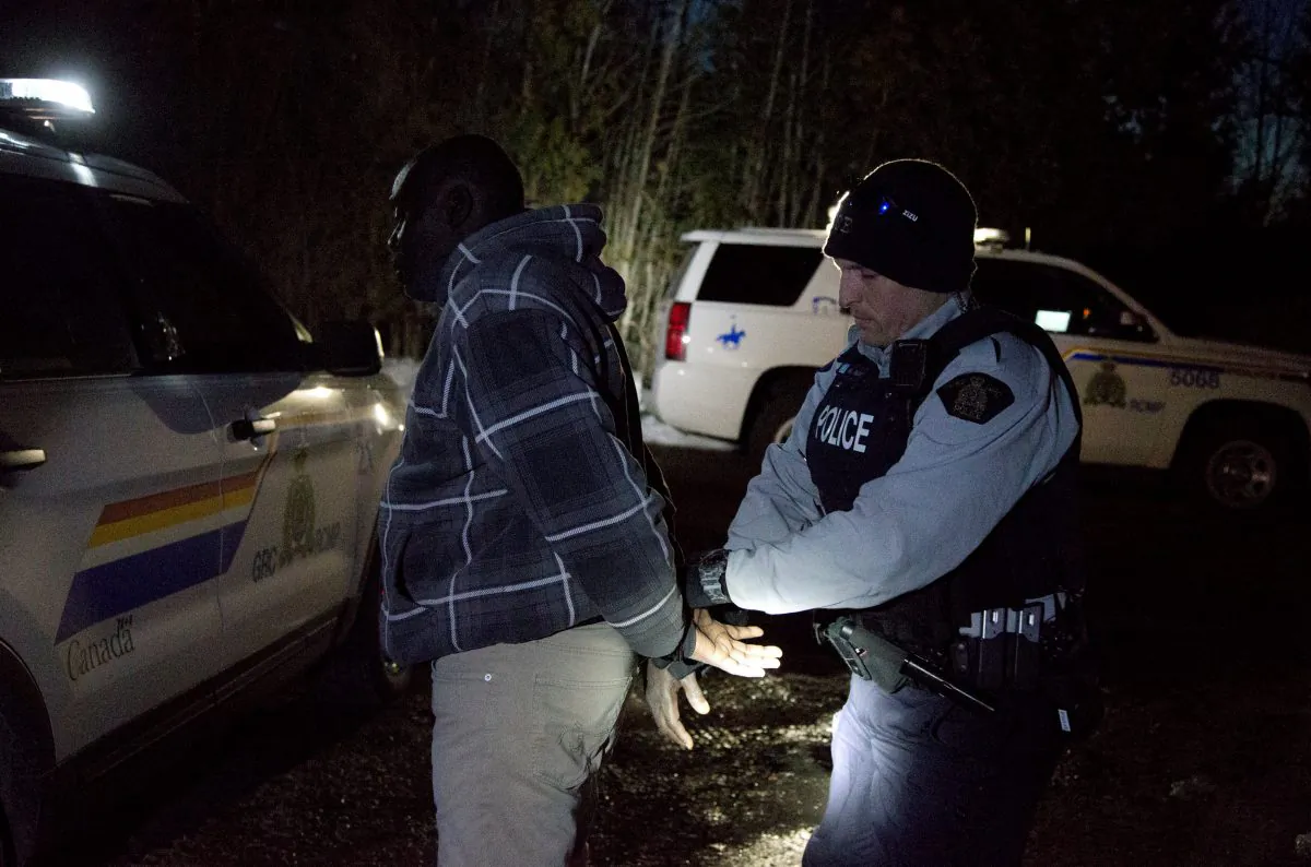 A man who claimed to be from Sudan is handcuffed by a Royal Canadian Mounted Police (RCMP) officer after he illegally crossed the U.S.-Canada border leading into Hemmingford, Quebec, Canada on March 20, 2017. (REUTERS/Christinne Muschi)