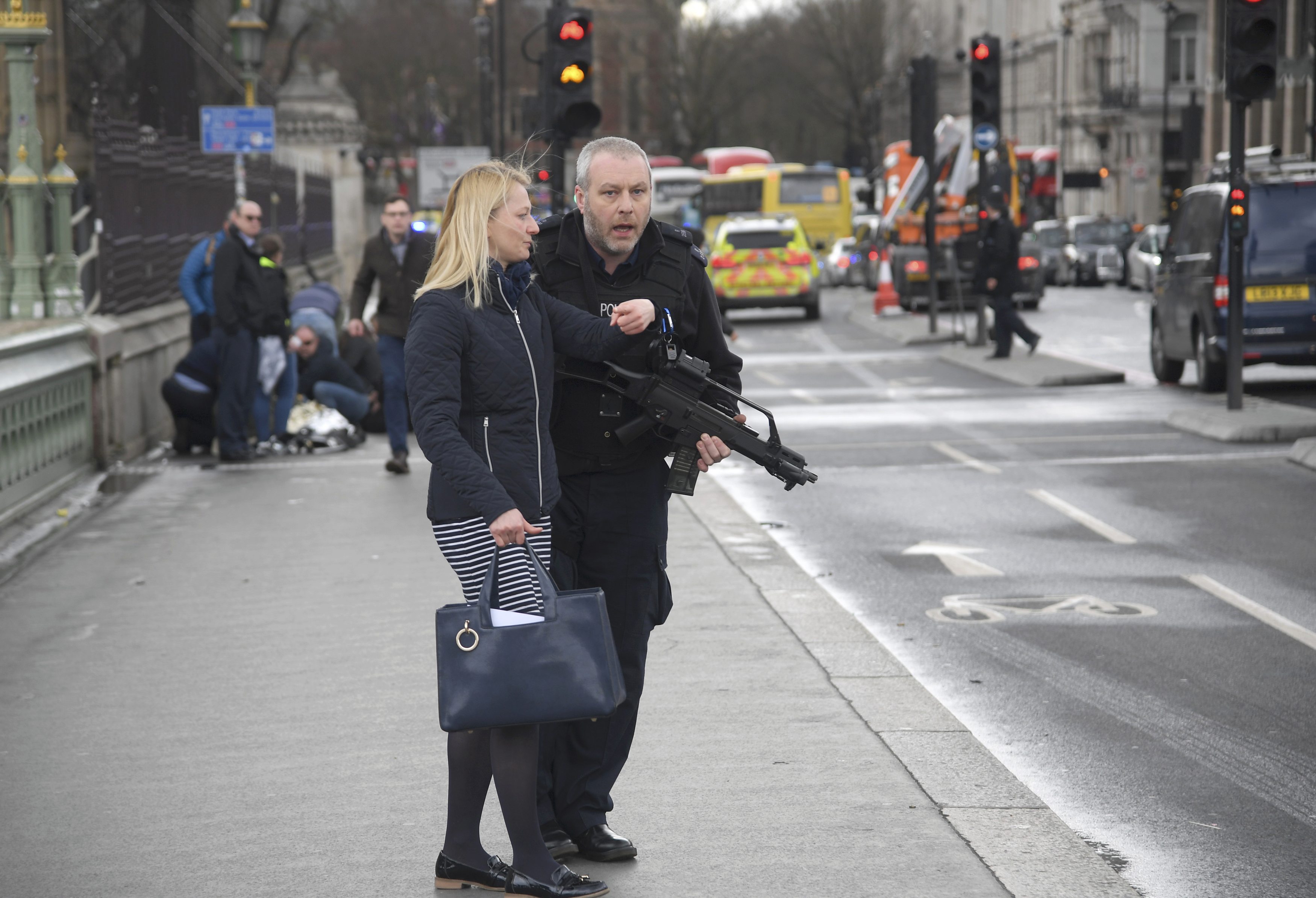 An armed police officer assists a woman after an incident on Westminster Bridge in London on March 22, 2017. (REUTERS/Toby Melville)