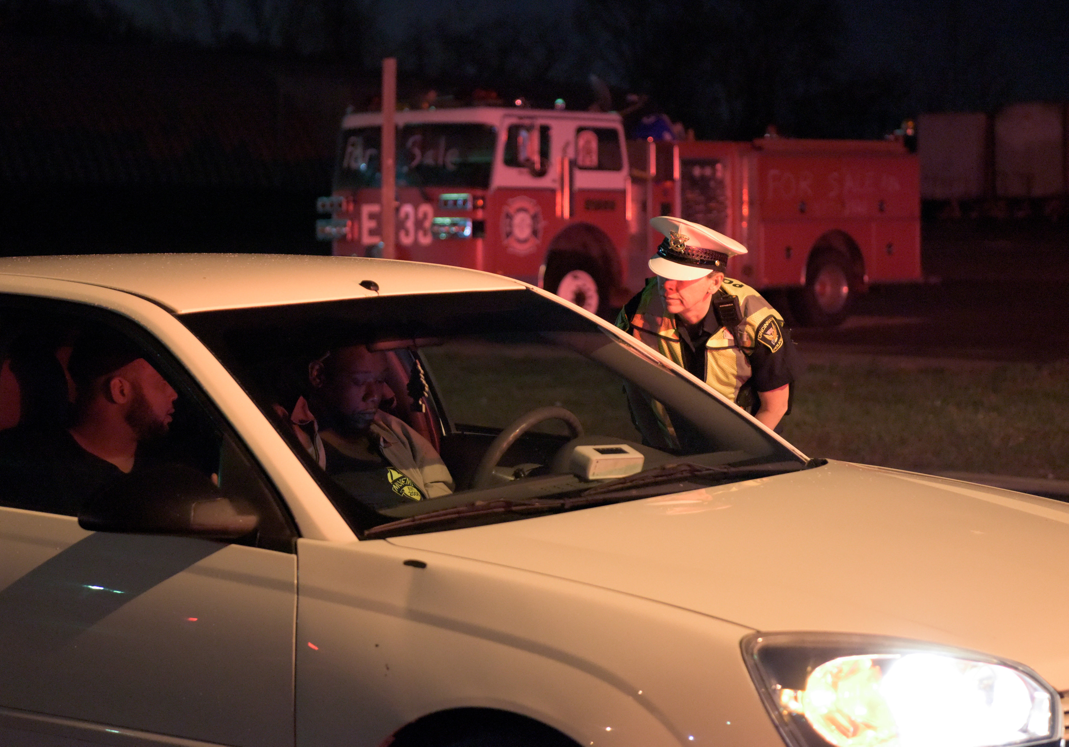 A Cincinnati Police officer tells occupants of a vehicle to turn back, at a roadblock near the scene of a mass shooting at the Cameo Nightlife club in Cincinnati, Ohio, on March 26, 2017. (REUTERS/Caleb Hughes)