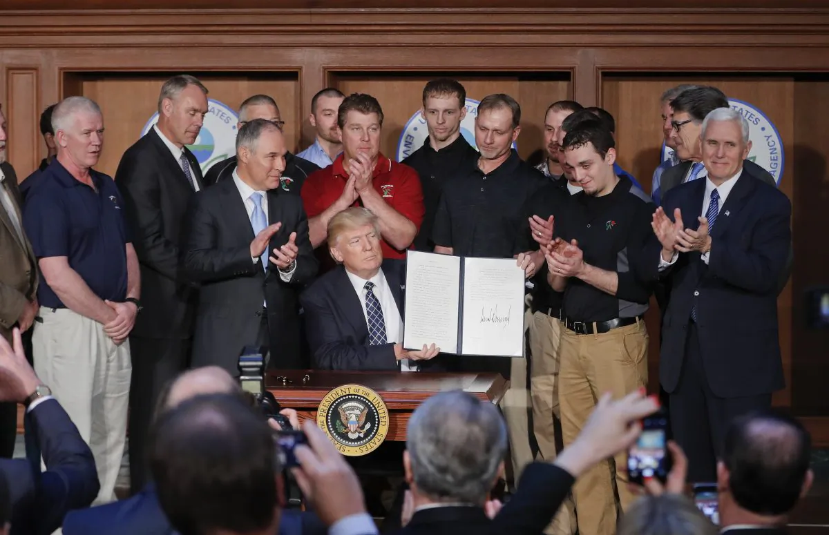 President Donald Trump, accompanied by Environmental Protection Agency (EPA) Administrator Scott Pruitt (3rd L) and Vice President Mike Pence (R) is applauded as he hold up the signed Energy Independence Executive Order at EPA headquarters in Washington on March 28, 2017. (Pablo Martinez Monsivais/AP Photo)