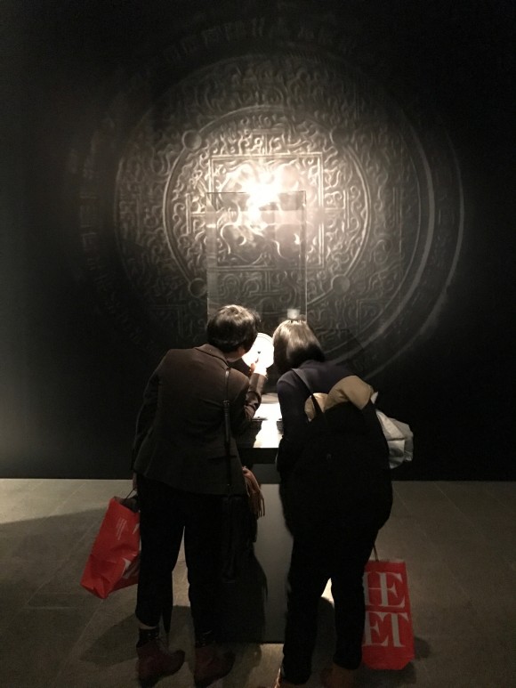 Two women look at the Han Dynasty mirror on display at the "Age of Empires" exhibition at The Metropolitan Museum of Art. (Milene Fernandez/Epoch Times)