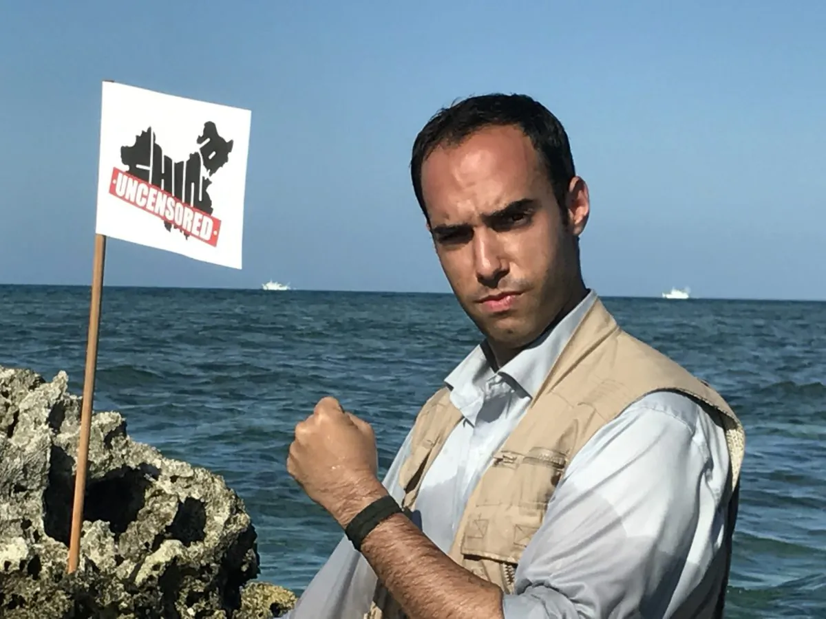 China Uncensored host Chris Chappell stands on the Scarborough Shoal in disputed waters. Two Chinese Coast Guard ships are visible in the background. November 14, 2016. (Matt Gnaizda/China Uncensored)