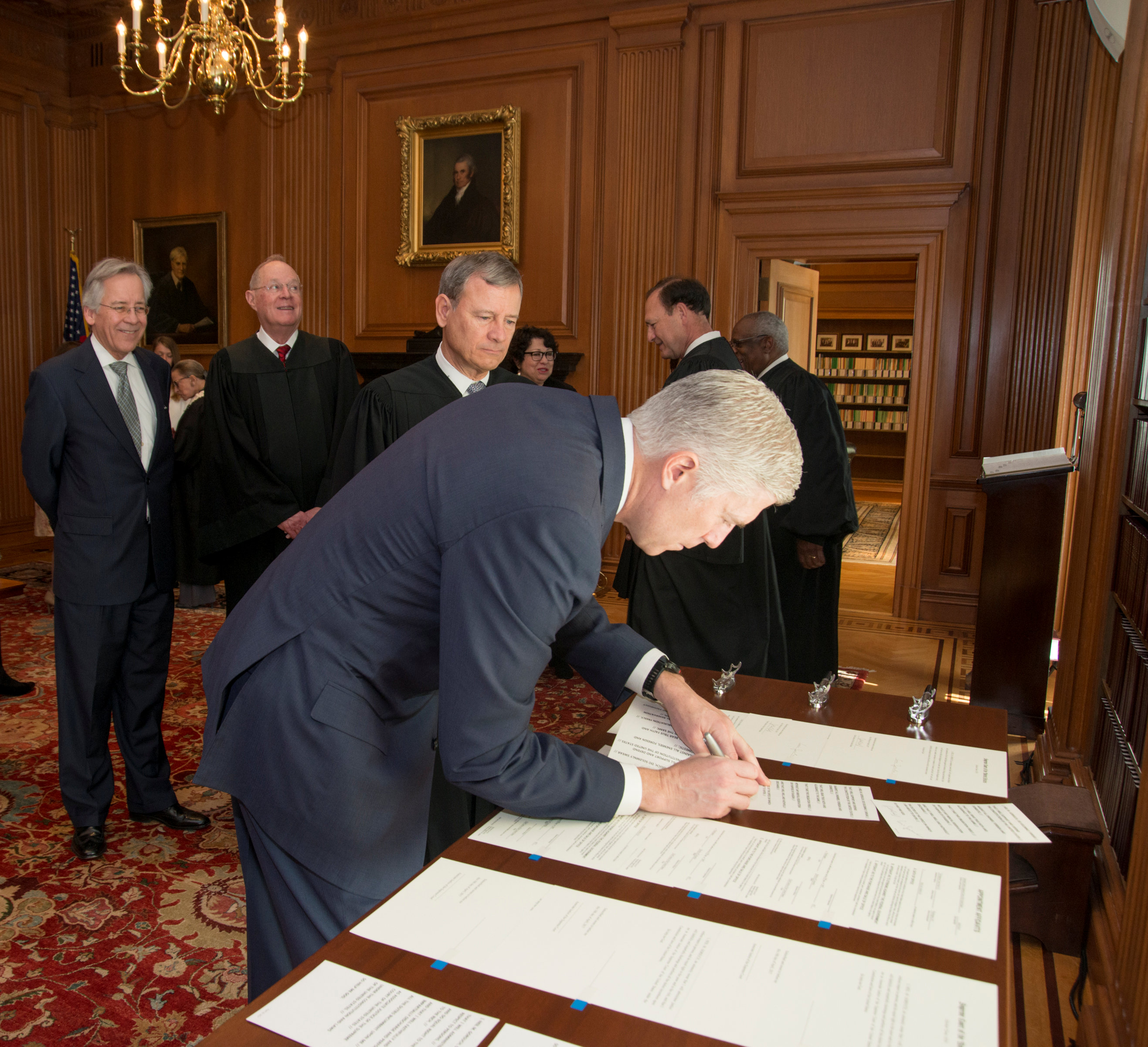 Chief Justice of the United States John Roberts (C) looks on as Judge Neil Gorsuch (R) signs the constitutional oath during swearing-in ceremony at the Supreme Court in Washington on April 10, 2017. (Courtesy Supreme Court of the United States/Handout via REUTERS)