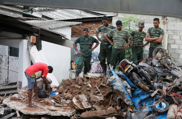 A man opens a bag next to military officers during a rescue mission after a garbage dump collapsed and buried dozens of houses in Colombo, Sri Lanka April 15, 2017. (REUTERS/Dinuka Liyanawatte)