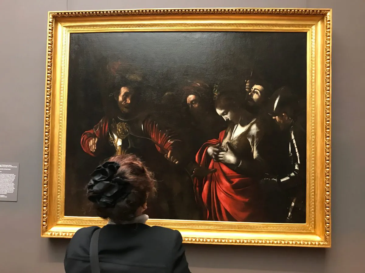 A woman looks at "The Martyrdom of Saint Ursula," 1610, by Caravaggio (Michelangelo Merisi, Italian, 1571–1610). Oil on canvas, Intesa Sanpaolo Collection, Palazzo Zevallos Stigliano, Naples. (Milene Fernandez/The Epoch Times)