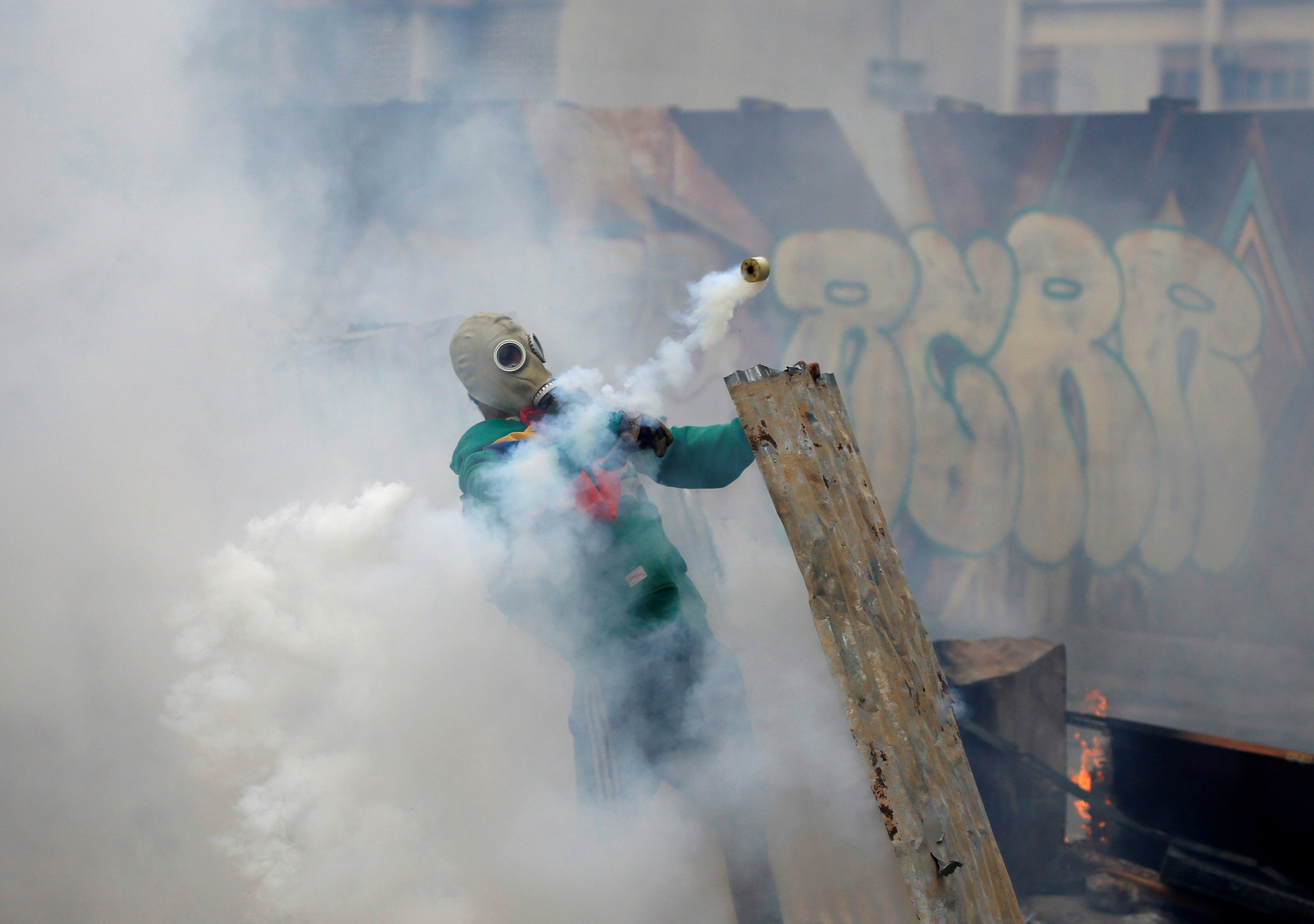 An opposition demonstrator throws back a gas grenade while clashing with riot police during the so called "mother of all marches" against Venezuela's President Nicolas Maduro in Caracas, Venezuela on April 19, 2017. (REUTERS/Carlos Garcia Rawlins)