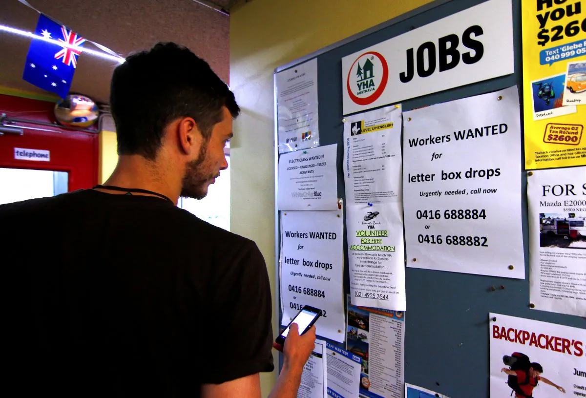A man uses his phone to record a job add posted on a notice board at a backpacker hostel in Sydney, Australia on May 9, 2016. (REUTERS/Steven Saphore)