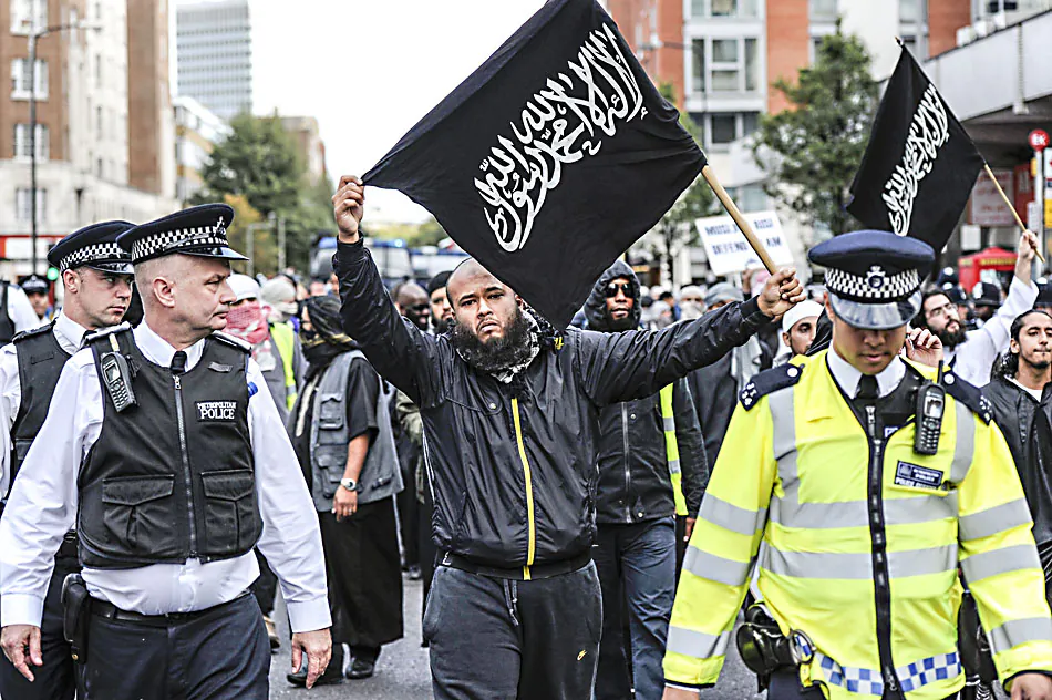 Police escort Islamist demonstrator marching to protest outside the US embassy in London before a ceremony to mark the 10th anniversary of the 9/11 attacks on the United States on Sept. 11, 2011. Around 50 people brandished anti-US banners, chanted slogans and burnt a small piece of paper with a picture of the US flag on it. (CARL COURT/AFP/Getty Images)