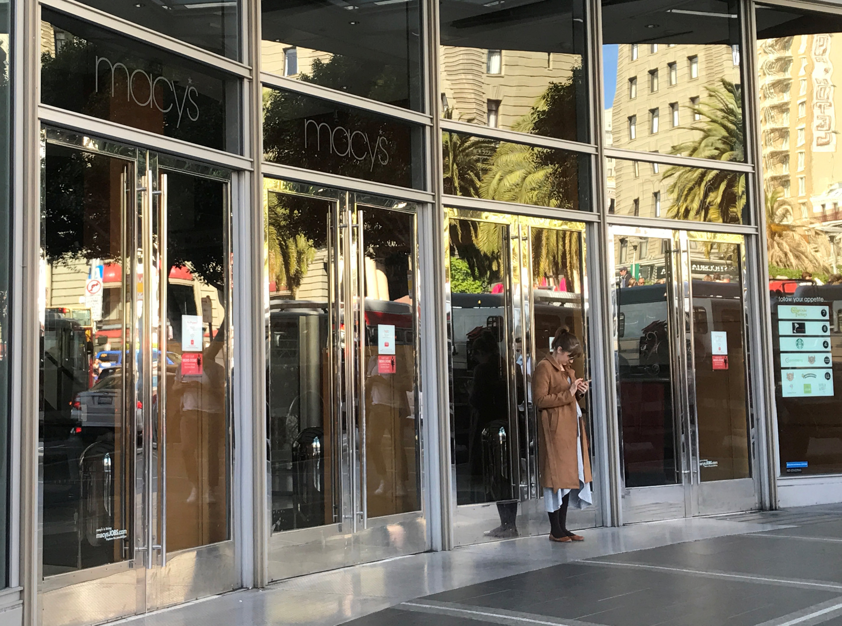 An employee stands outside the closed doors of Macy's department store, during a power cut in San Francisco, Calif., April 21, 2017. (REUTERS/Alexandria Sage)