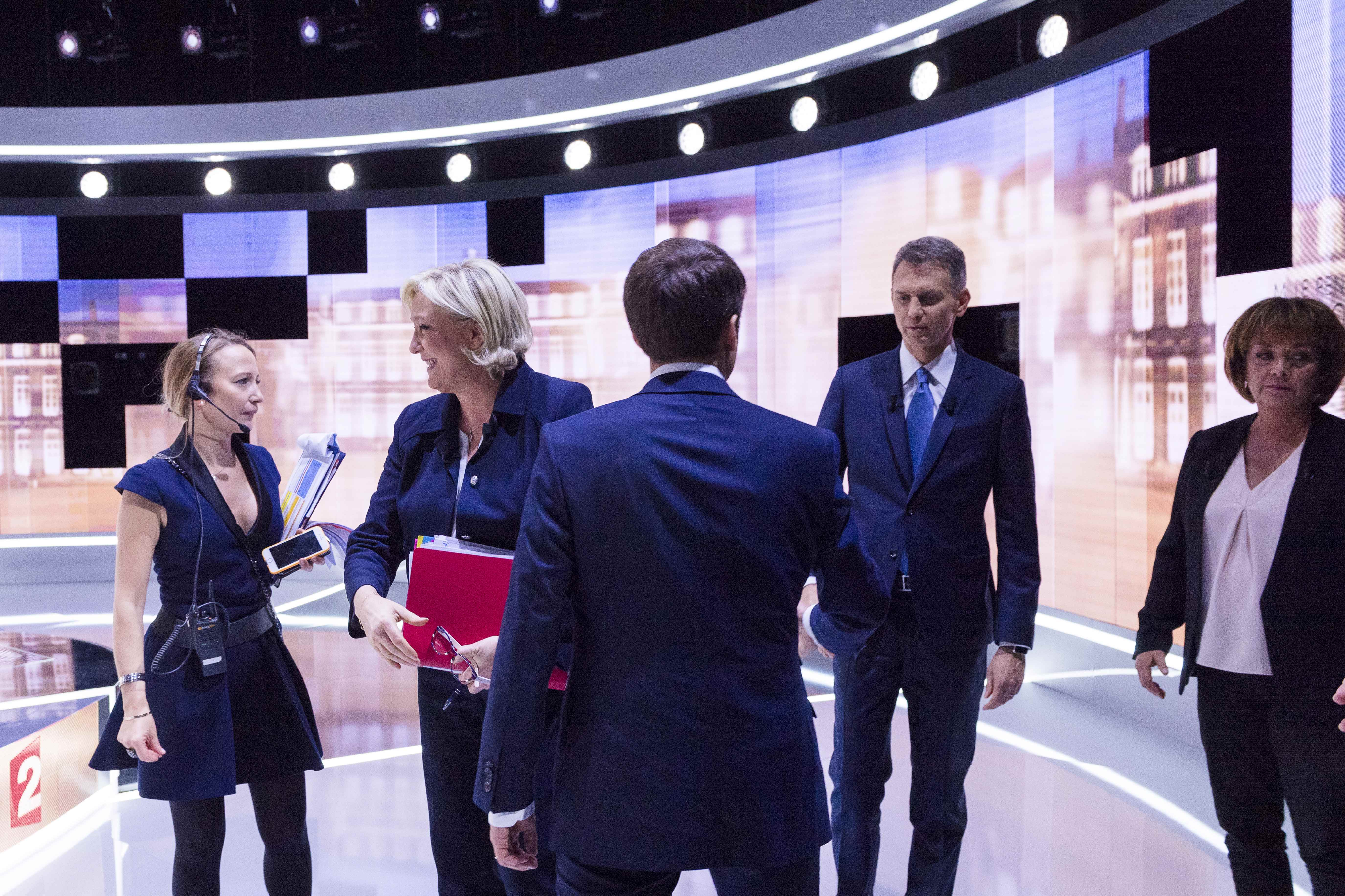 French presidential candidate Marine Le Pen (2ndL), French journalist Christophe Jakubyszyn (Rear 2ndR), French journalist Nathalie Saint-Cricq (R) and French presidential election candidate Emmanuel Macron (C) on the set prior to the start of a live broadcast televised debate in the studios of French public national television channel France 2, and French private channel TF1 in La Plaine-Saint-Denis, near Paris, France, May 3, 2017. (REUTERS/Eric Feferberg/Pool)