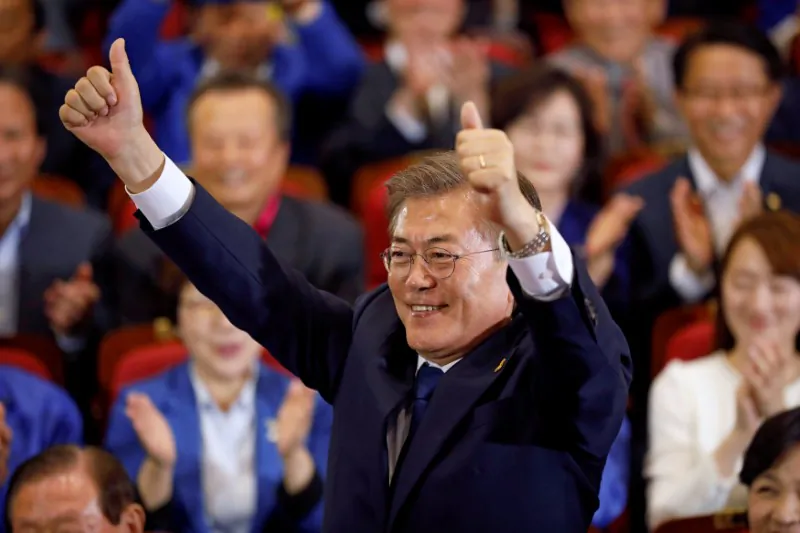 Moon Jae-in, the presidential candidate of the Democratic Party of Korea, poses for photographs as he watches a television report on an exit poll of the presidential election in Seoul, South Korea on May 9, 2017. (REUTERS/Kim Hong-Ji)