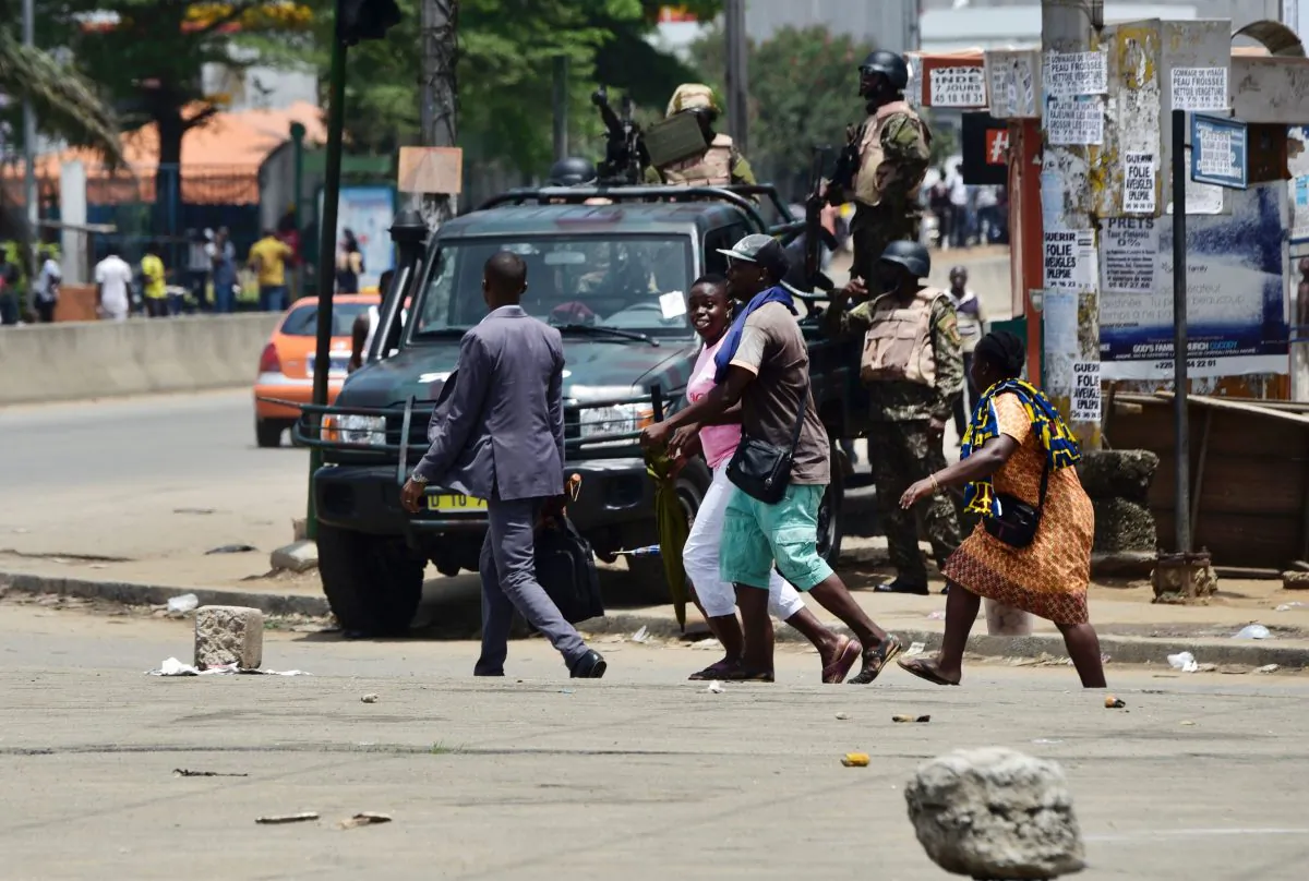 People walk past soldiers of the Republican Guard standing in the street going to the Akouedo's military camp, in Abidjan, Ivory Coast, on May 15, 2017. (Sia Kambou/AFP/Getty Images)