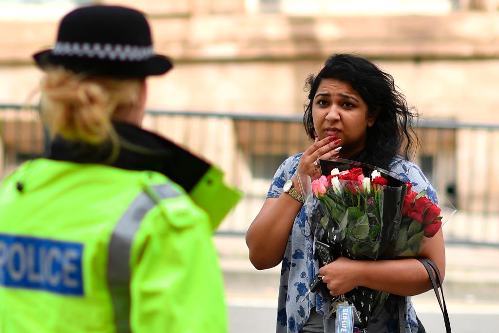 A police officer (L) talks with a woman carrying a bunch of flowers near the Manchester Arena in Manchester, northwest England on May 23, 2017. (BEN STANSALL/AFP/Getty Images)