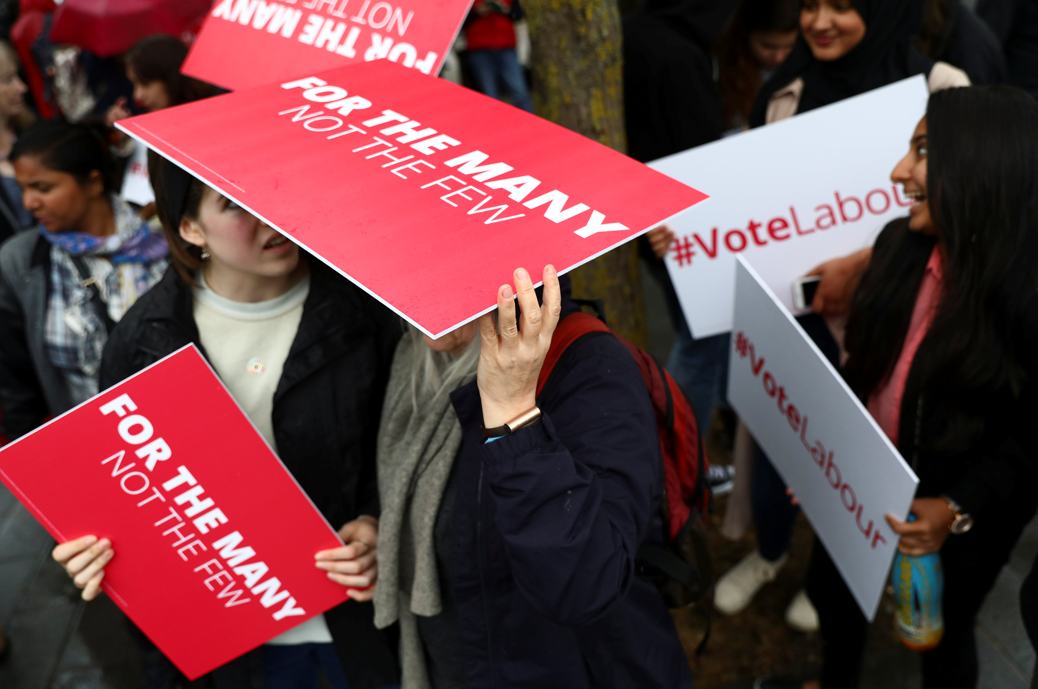 Supporters of Britain's opposition Labour party use placards to shelter from the rain as they campaign in London, Britain on May 18, 2017. (REUTERS/Neil Hall)