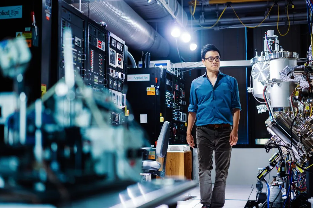 Dr. Jeehwan Kim, a mechanical engineering professor at MIT, with the molecular beam epitaxy system that manufactures semiconductor divices such as the lasers used to read CDs. (Lillie Paquette/MIT School of Engineering) 