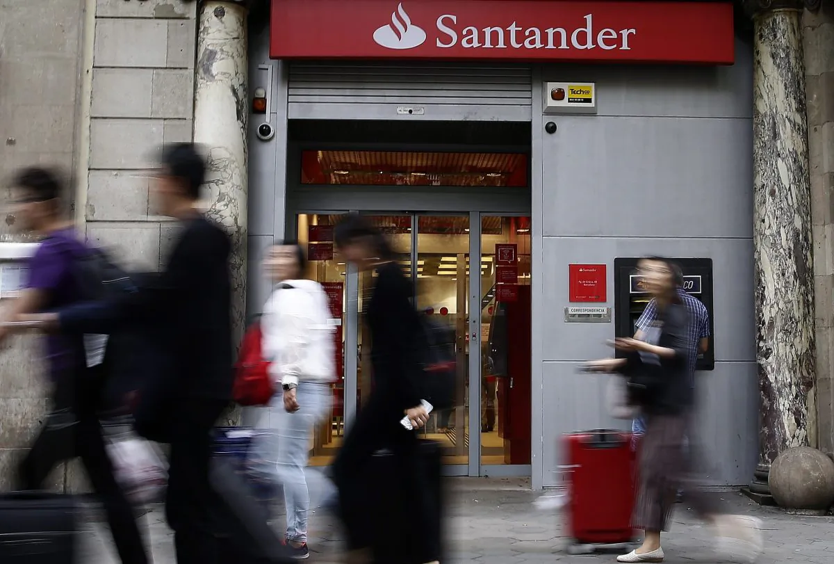In this file photo, people walk past a Banco Santander office in Barcelona.  (AP Photo/Manu Fernandez)