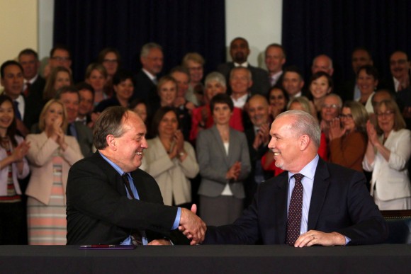B.C. NDP leader John Horgan and B.C. Green party leader Andrew Weaver shake hands after signing an agreement to create a stable minority government during a press conference at the Victoria legislature on May 30, 2017. (The Canadian Press/Chad Hipolito)