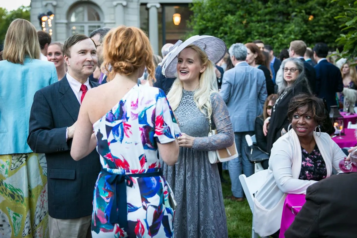 Alexis Light, senior manager of media relations and marketing for The Frick (front), speaks with artist Annika Connor and another guest in The Frick’s Fifth Avenue Garden during the Spring Garden Party for Fellows of The Frick Collection on June 7. (Benjamin Chasteen/The Epoch Times)