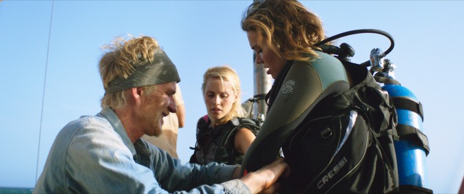 (L–R) Kate (Claire Holt) and Lisa (Mandy Moore) suit-up with the help of Captain Taylor (Matthew Modine) for an unforgettable underwater shark dive  in 