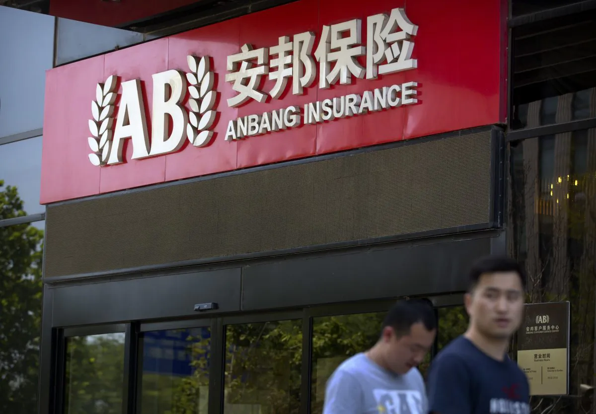People walk past an entrance to the Anbang Group's offices in Beijing on June 14. (AP Photo/Mark Schiefelbein)