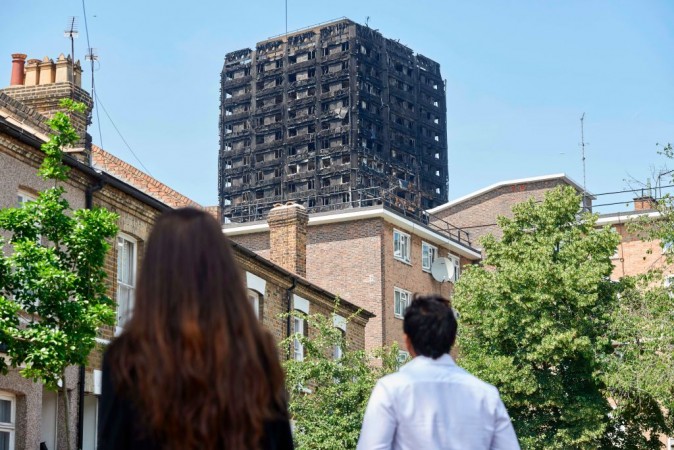 The burned-out shell of the Grenfell Tower block is seen behind terraced houses as local residents look on near the scene of the fire in North Kensington, west London on June 20, 2017. (Niklas Halle'n/AFP/Getty Images)