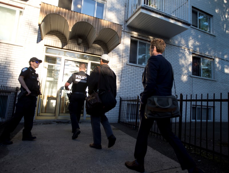 Police investigators walk into the residence of Amor Ftouhi, in Montreal, Quebec, Canada on June 21, 2017. (REUTERS/Christinne Muschi)
