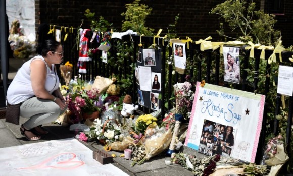 A woman looks at flowers, tributes and messages left for the victims of the fire at the Grenfell apartment tower in North Kensington, London, Britain, June 23, 2017. (Reuters/Hannah McKay)