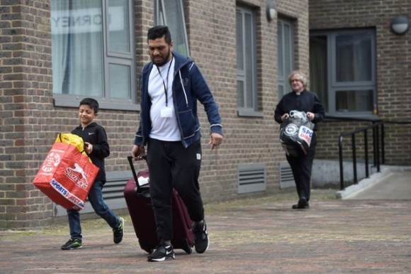 A priest helps a family move from the Dorney Tower residential block during an evacuation as a precautionary measure following concerns over the type of cladding used on the outside of the building on the Chalcots Estate in north London, Britain, June 24, 2017. (Reuters/Hannah McKay)