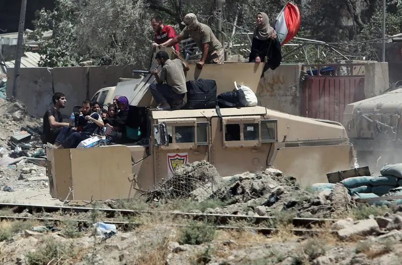 Iraqi security forces transport displaced civilians with an armoured fighting vehicle out of West Mosul during fighting with Islamic State militants in the Old City of Mosul, Iraq June 24, 2017. (Reuters/Marius Bosch)