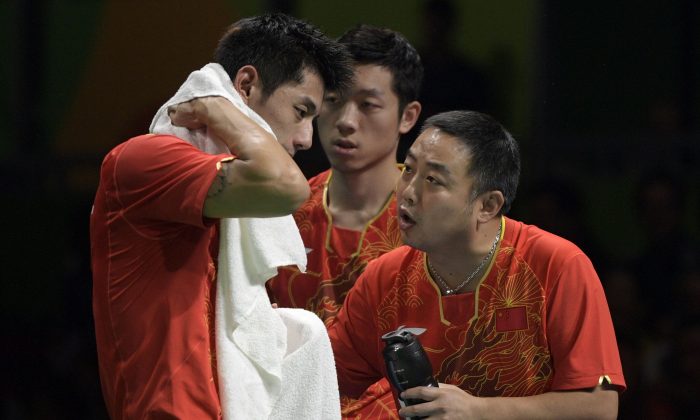 China's Zhang Jike (L) is counseled by his coach Liu Guoliang (R) after losing a game in the men's team semi-final table tennis match against South Korea at the Riocentro venue during the Rio 2016 Olympic Games in Rio de Janeiro on August 15, 2016. (JUAN MABROMATA/AFP/Getty Images)