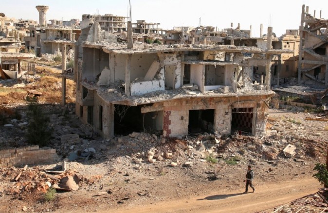 A rebel fighter walks past damaged buildings in a rebel-held part of the southern city of Deraa, Syria on June 22, 2017. (REUTERS/Alaa Al-Faqir)