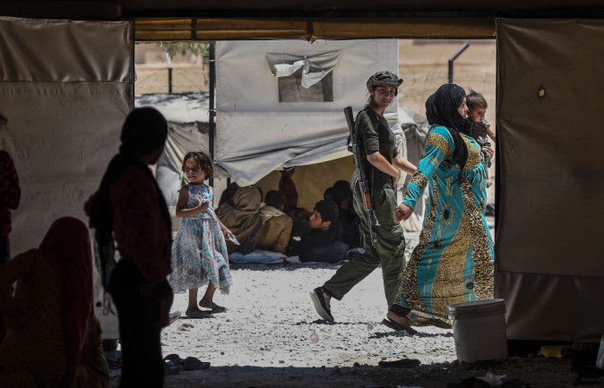 A female fighter from the Kurdish Women's Protection Units walks among Syrians who fled the countryside surrounding the ISIS stronghold of Raqqa at a refugee camp in the village of Ayn Issa, Syria, on July 11, 2017. (BULENT KILIC/AFP/Getty Images)