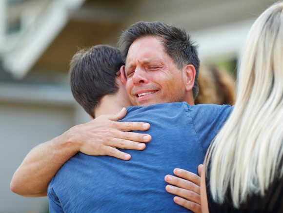Don Damond hugs a neighbor after reading a statement about his fiance, Justine Damond who was fatally shot by Minneapolis police in Minneapolis, Minnesota, U.S., July 17, 2017. REUTERS/Adam Bettcher