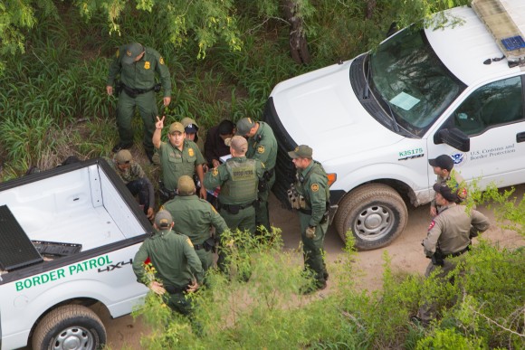 A Border Patrol agent signals to the Customs and Border Protection helicopter crew that two aliens from a group of seven they tried to capture have escaped, near Salineno, Texas, on May 30. (Benjamin Chasteen/The Epoch Times)