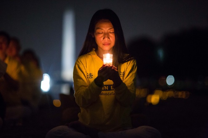 A woman joins Falun Gong practitioners hold a candlelight vigil at the Lincoln Memorial in Washington on July 20, 2017, to honor those who have died during the persecution in China that the Chinese regime started on July 20, 1999. (Benjamin Chasteen/The Epoch Times)