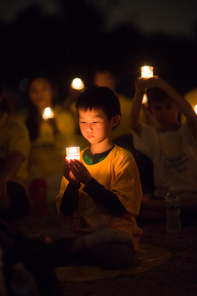 A little boy joins Falun Gong practitioners hold a candlelight vigil at the Lincoln Memorial in Washington on July 20, 2017, to honor those who have died during the persecution in China that the Chinese regime started on July 20, 1999. (Benjamin Chasteen/The Epoch Times)