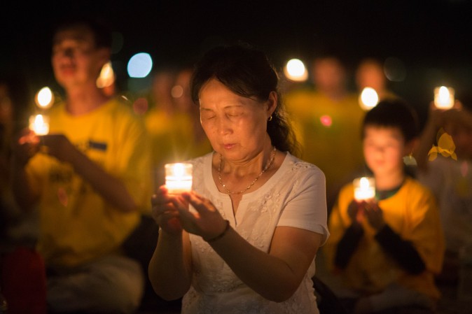 A woman joins Falun Gong practitioners hold a candlelight vigil at the Lincoln Memorial in Washington on July 20, 2017, to honor those who have died during the persecution in China that the Chinese regime started on July 20, 1999. (Benjamin Chasteen/The Epoch Times)